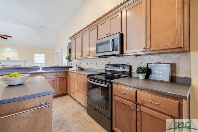 kitchen featuring sink, lofted ceiling, light tile patterned floors, decorative backsplash, and appliances with stainless steel finishes