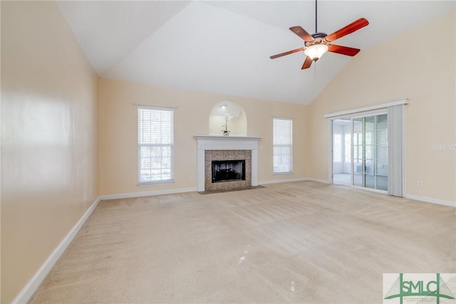 unfurnished living room with high vaulted ceiling, a tiled fireplace, ceiling fan, and light colored carpet