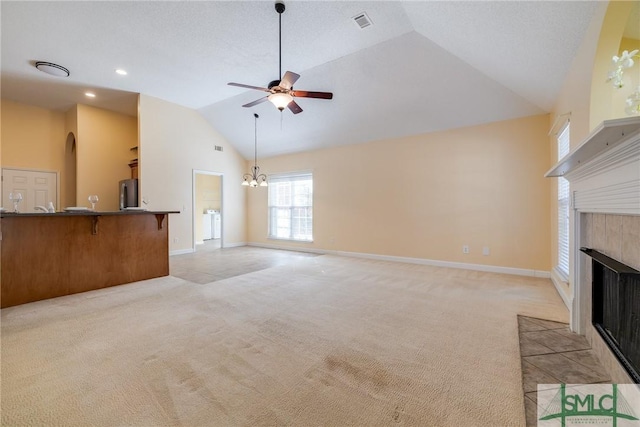 unfurnished living room with lofted ceiling, a fireplace, light carpet, and ceiling fan with notable chandelier