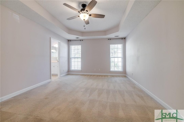 carpeted spare room featuring ceiling fan, a textured ceiling, and a tray ceiling