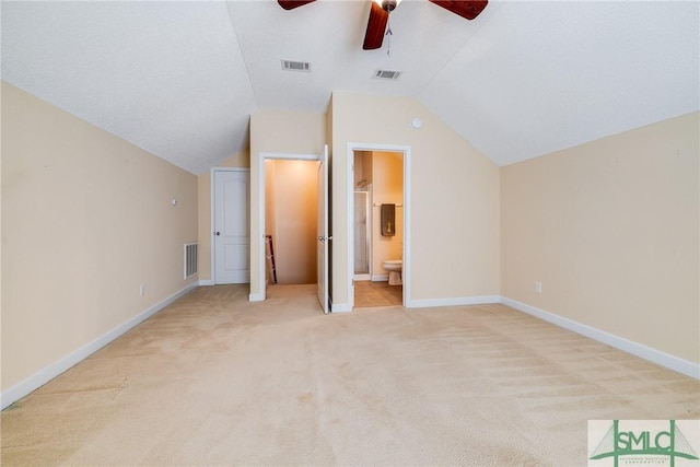 unfurnished bedroom featuring lofted ceiling, ensuite bath, ceiling fan, and light colored carpet