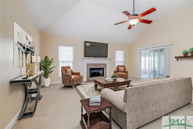 living room featuring a tiled fireplace, light colored carpet, vaulted ceiling, and ceiling fan