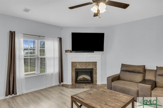 living room with light hardwood / wood-style floors, ceiling fan, and a fireplace