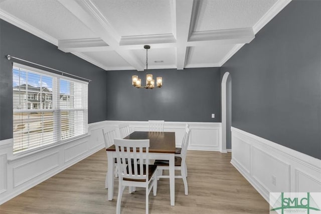 dining room featuring a notable chandelier, beamed ceiling, light hardwood / wood-style flooring, coffered ceiling, and crown molding