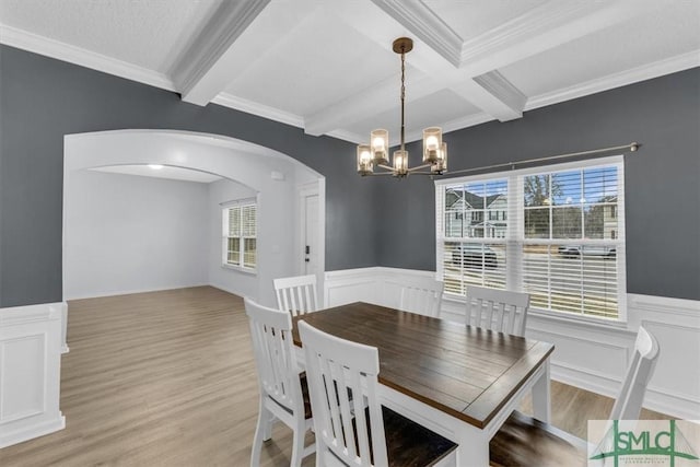 dining space with an inviting chandelier, ornamental molding, light hardwood / wood-style floors, coffered ceiling, and beam ceiling