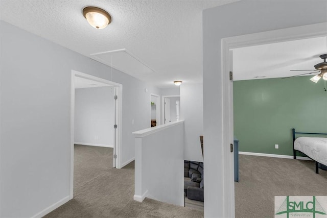 corridor featuring light colored carpet and a textured ceiling