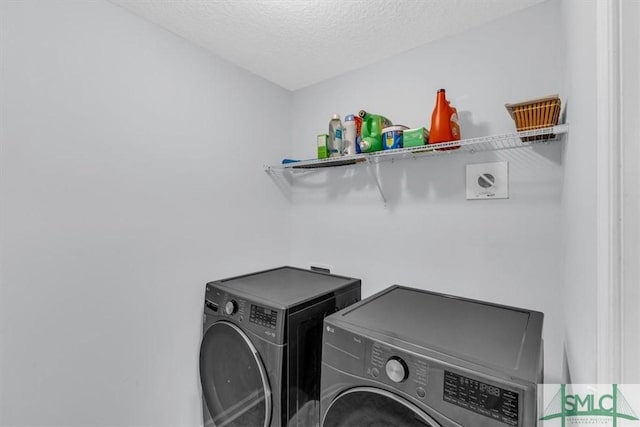 laundry room with a textured ceiling and washer and clothes dryer