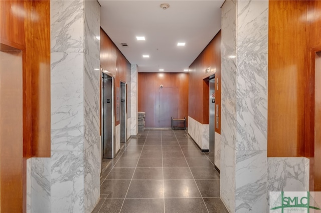 hallway featuring tile walls and elevator