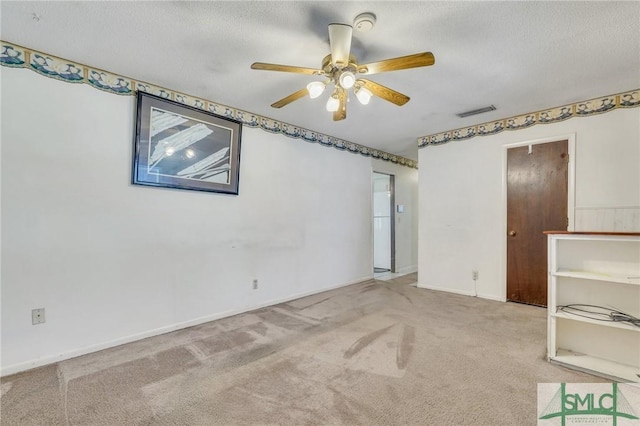 carpeted empty room featuring a textured ceiling and ceiling fan