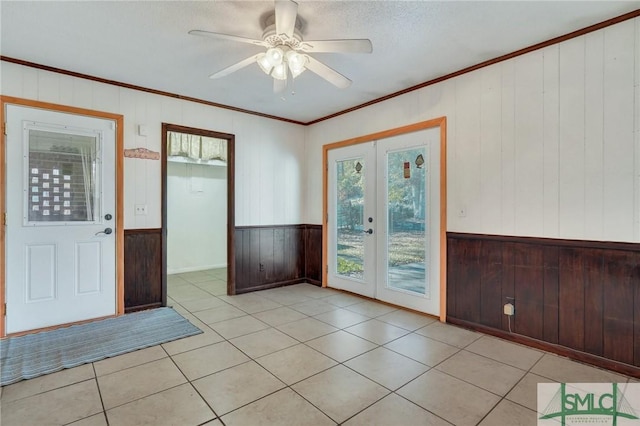 doorway to outside with french doors, light tile patterned flooring, ceiling fan, and wooden walls