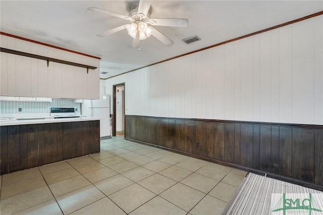 kitchen featuring range, wooden walls, white refrigerator, ornamental molding, and dark brown cabinets