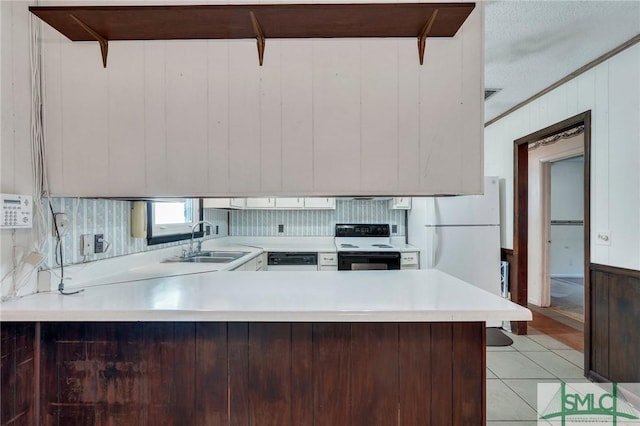 kitchen featuring electric stove, kitchen peninsula, white refrigerator, wooden walls, and sink