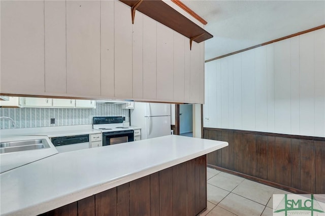 kitchen with white appliances, wood walls, dark brown cabinets, and sink