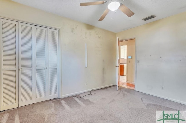 unfurnished bedroom with ceiling fan, a closet, and light carpet