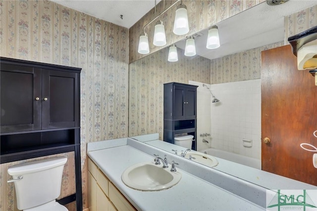 full bathroom featuring tiled shower / bath, vanity, and toilet