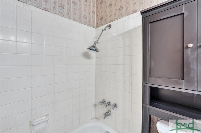 bathroom featuring toilet and tiled shower / bath combo