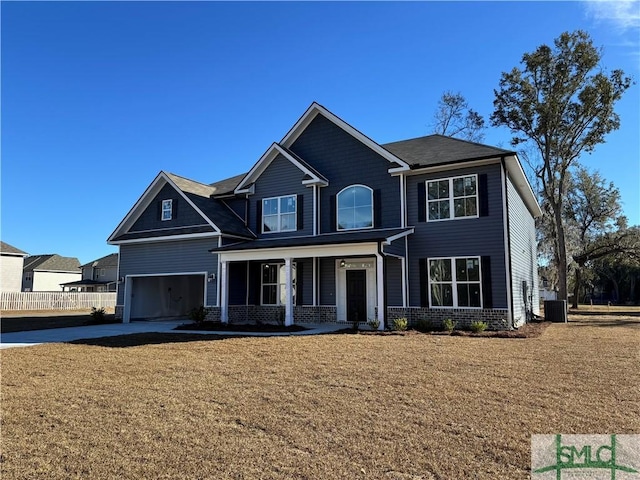 view of front of house featuring covered porch, cooling unit, a garage, and a front yard