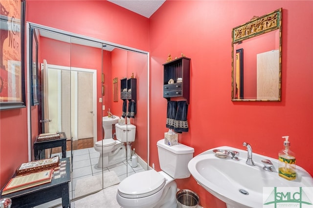 bathroom with toilet, tile patterned flooring, a textured ceiling, and sink