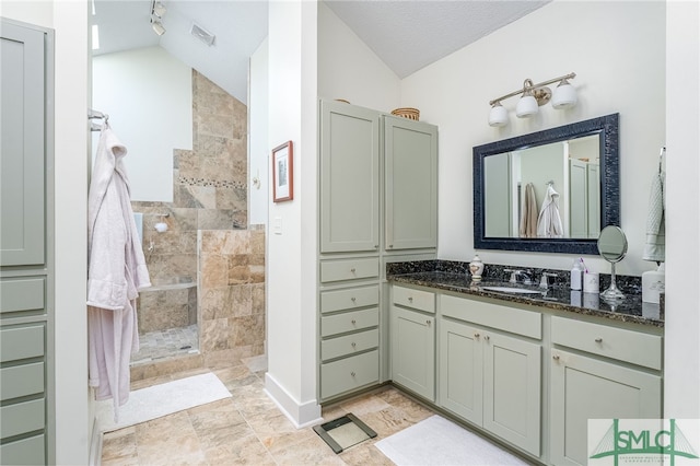 bathroom featuring lofted ceiling, a textured ceiling, a shower, and vanity