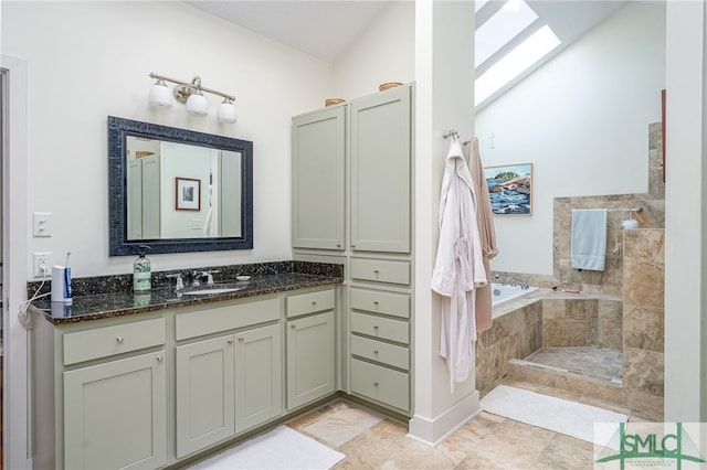 bathroom featuring a skylight, tiled tub, and vanity