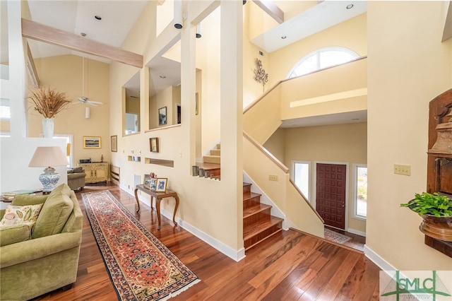 living room with a towering ceiling, wood-type flooring, and ceiling fan