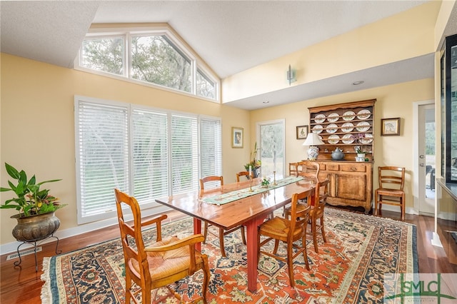 dining area with high vaulted ceiling, a healthy amount of sunlight, and hardwood / wood-style floors