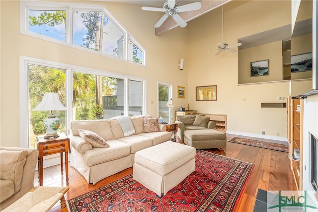 living room with a towering ceiling, ceiling fan, and hardwood / wood-style floors