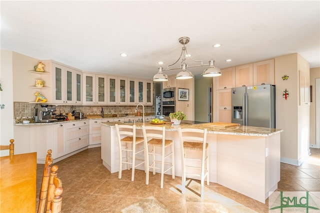 kitchen featuring stainless steel appliances, a center island with sink, a kitchen breakfast bar, and decorative backsplash