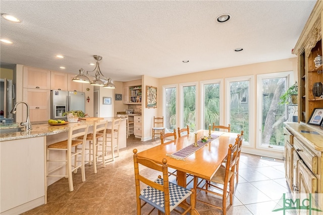 dining area featuring sink, light tile patterned floors, a textured ceiling, and a wealth of natural light