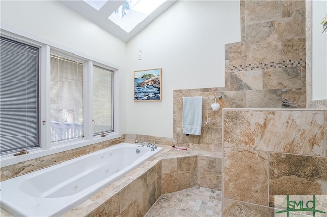 bathroom featuring tiled tub and vaulted ceiling with skylight