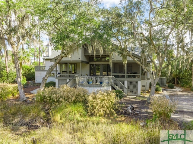 rear view of property featuring a sunroom and a wooden deck