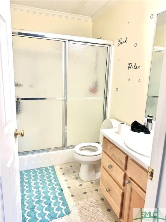 bathroom featuring toilet, vanity, a shower with shower door, and crown molding