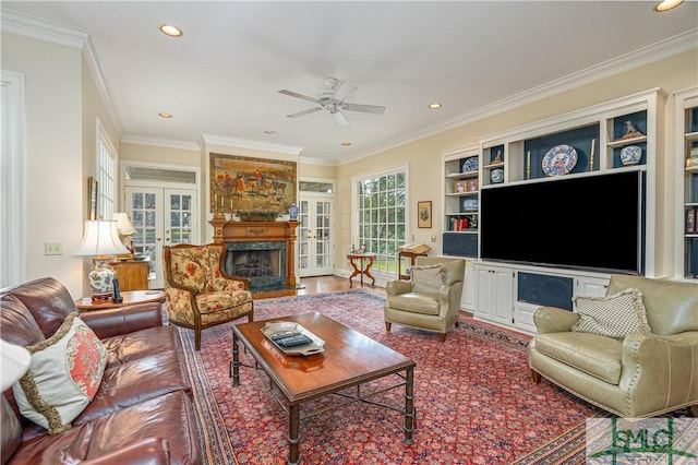 living room featuring a premium fireplace, french doors, crown molding, built in features, and ceiling fan