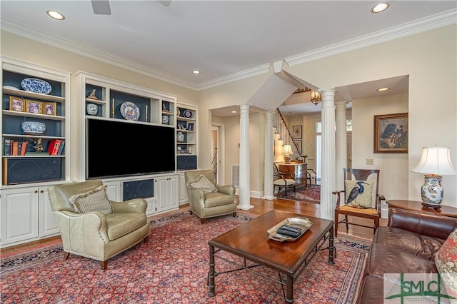 living room featuring built in shelves, ornamental molding, and ornate columns