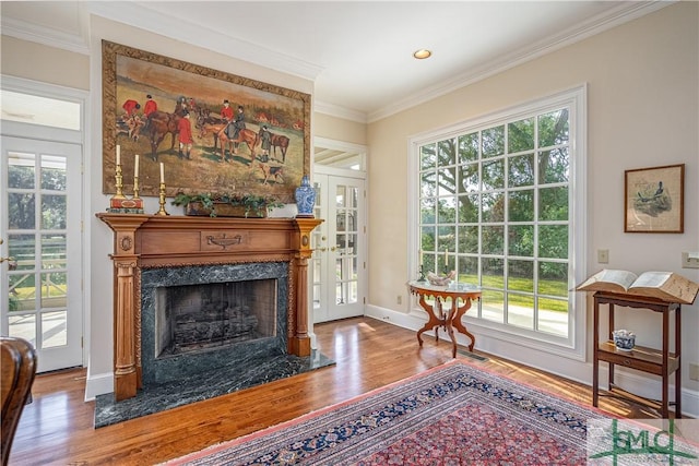 living area with crown molding, a fireplace, and hardwood / wood-style flooring