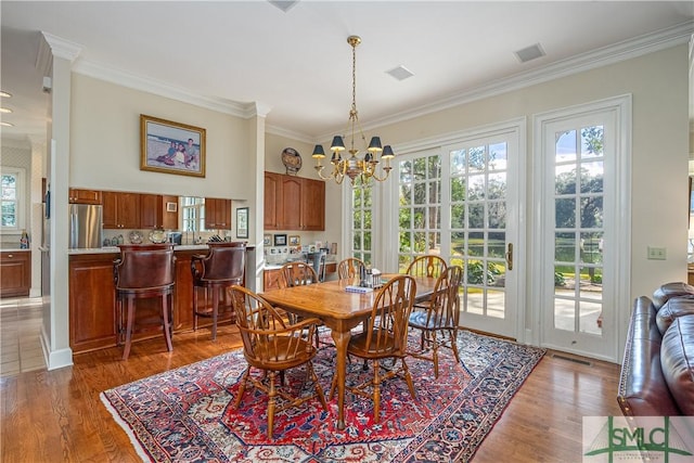 dining room with a notable chandelier, ornamental molding, and hardwood / wood-style floors