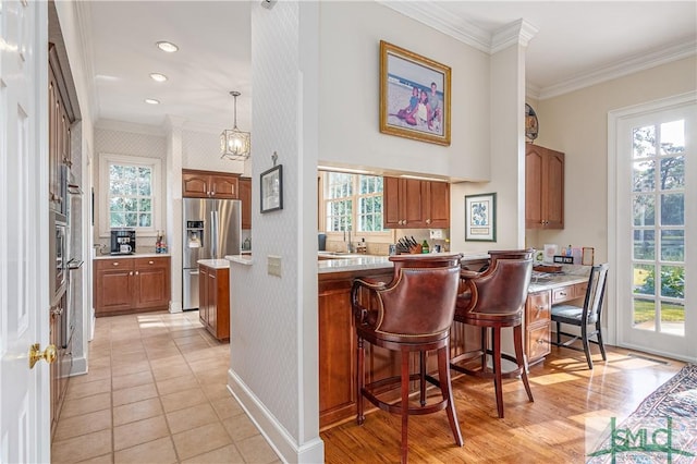 kitchen featuring decorative light fixtures, light tile patterned floors, a breakfast bar, stainless steel refrigerator with ice dispenser, and ornamental molding