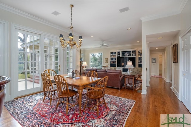 dining area featuring ceiling fan with notable chandelier, wood-type flooring, and ornamental molding