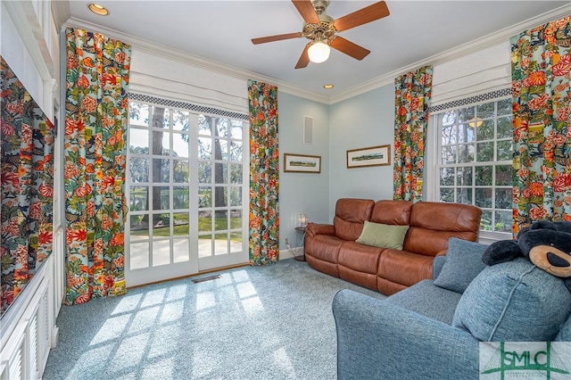 living room with ceiling fan, plenty of natural light, and crown molding