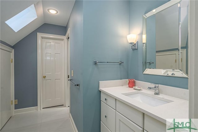 bathroom with tile patterned flooring, lofted ceiling with skylight, and vanity