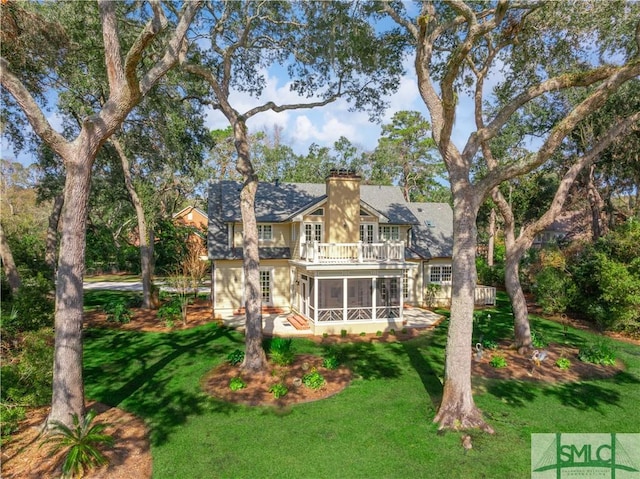 back of property with a lawn and a sunroom