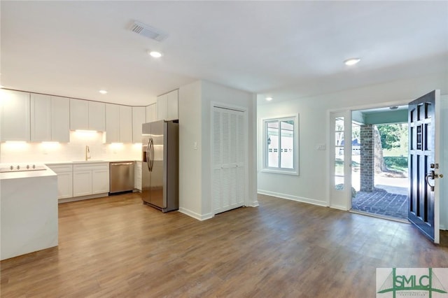 kitchen with stainless steel appliances, white cabinets, sink, and light hardwood / wood-style flooring