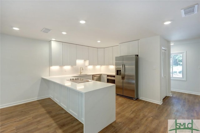 kitchen with stainless steel appliances, sink, white cabinets, kitchen peninsula, and light hardwood / wood-style flooring