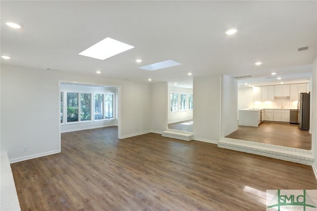 unfurnished living room with a skylight and hardwood / wood-style floors