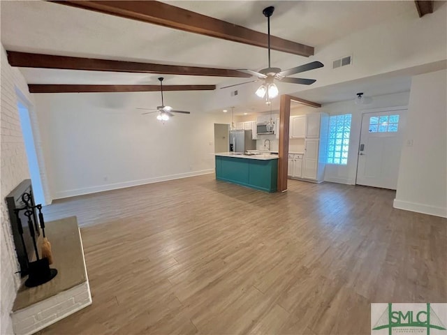 unfurnished living room with lofted ceiling with beams, ceiling fan, and light hardwood / wood-style flooring