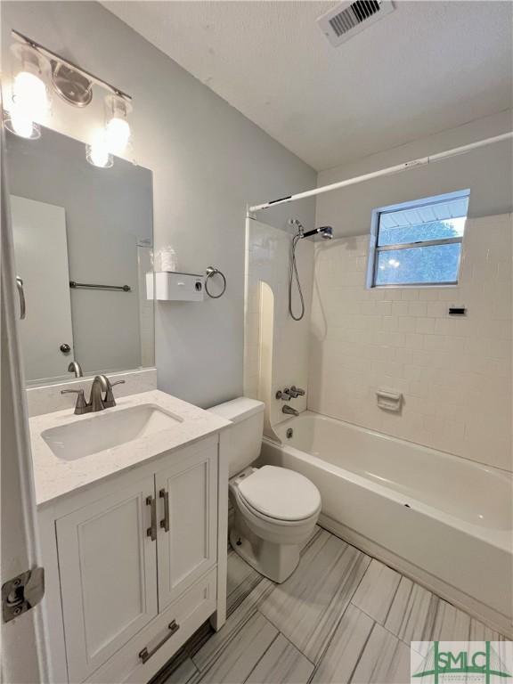 full bathroom featuring vanity, tiled shower / bath combo, and toilet