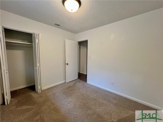 unfurnished bedroom with a textured ceiling, a closet, and carpet