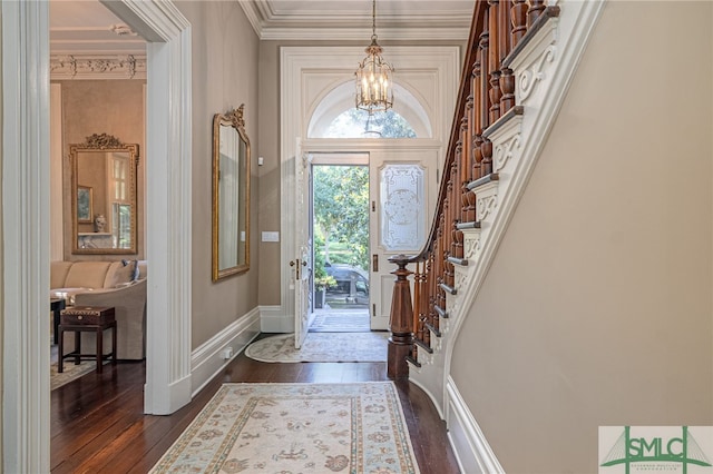 foyer entrance with an inviting chandelier, ornamental molding, and dark hardwood / wood-style flooring