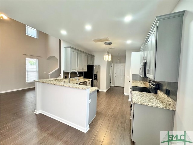 kitchen featuring decorative light fixtures, stainless steel appliances, dark hardwood / wood-style floors, gray cabinets, and light stone counters