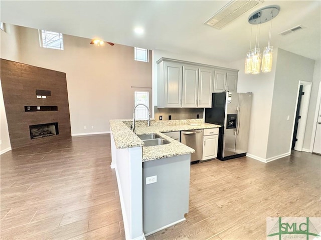 kitchen featuring a fireplace, light hardwood / wood-style floors, sink, appliances with stainless steel finishes, and light stone counters